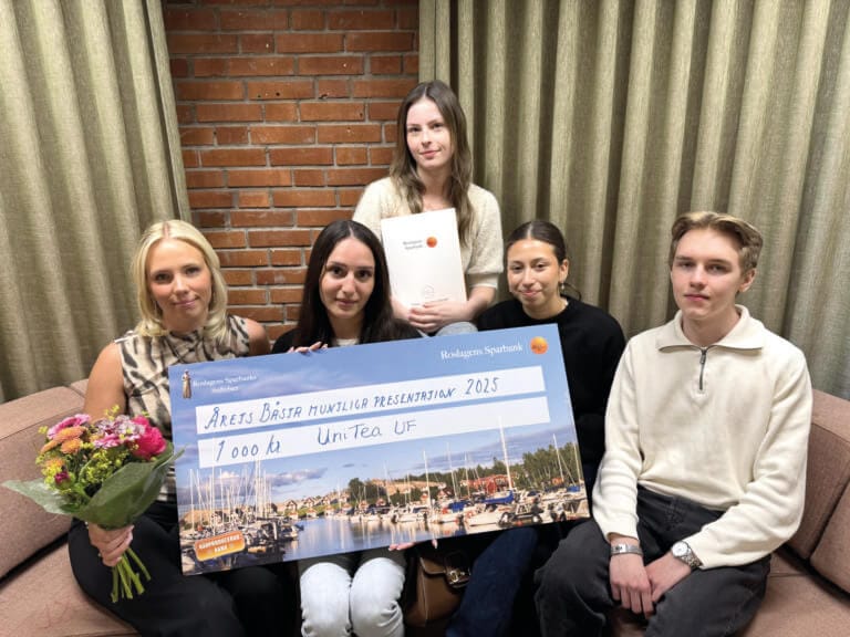 Fem prisade unga företagare sitter i en soffa och håller i en stor ceremoniell check på 7.000 kr, blommor och ett diplom. På checken står det "Årets Bästa Hantverkar presentation 2023, UniTech UF". I bakgrunden syns en gardin och en tegelvägg.