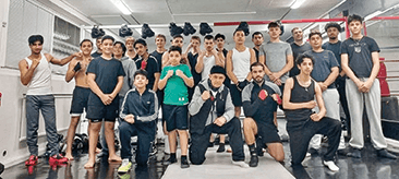 En stor grupp manliga boxare som poserar för ett foto i ett gym.